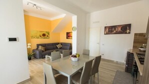 Una sala moderna con un sofá, una mesa de comedor con sillas y una zona de cocina.