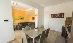 Een moderne woonkamer met een bank, een eettafel met stoelen en een keukenhoek.