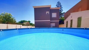 A swimming pool with a tiled edge, surrounded by a building with a flat roof and a small window.