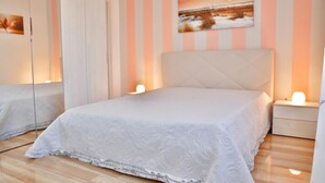 A bedroom with a large bed, a nightstand, a mirror, and a painting on the wall.