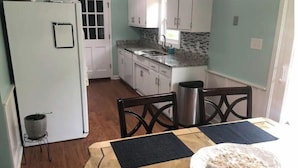 A compact kitchen with white cabinets, a granite countertop, and a stainless steel sink. - Cozy Home in Central Morehead 5min. from the Beach (Morehead City)