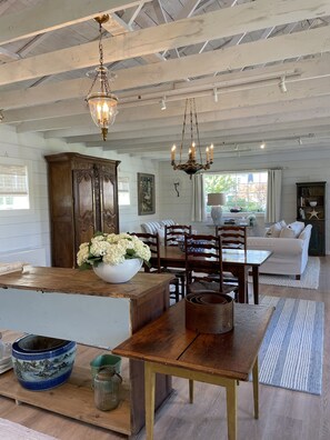 A spacious living area with a wooden dining table, a sofa, and a chandelier.