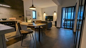 Une cuisine moderne avec un coin repas, un téléviseur et une porte-fenêtre coulissante donnant sur un espace extérieur.