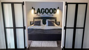 A bedroom with a bed, pillows, a rug, and a wall sign reading "LAGOOD People Planet Prosperity". - Lagood, modern splendid apartment, views of Lagos bay (Lagos)
