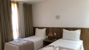 A hotel room with two beds, a nightstand, a lamp, and a wall-mounted light fixture. - Beach House Vacation Rental 15 to 22 July 2022 Costa do Sauípe BA (Mata de São João)