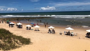 A beach with people, umbrellas, and chairs. - Beach House Vacation Rental 15 to 22 July 2022 Costa do Sauípe BA (Mata de São João)