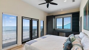 A bedroom with a bed, a ceiling fan, a TV, and large windows with a view of the ocean. - Beachfront Villa, Panoramic Deck & Private Beach (Ponte Vedra Beach)