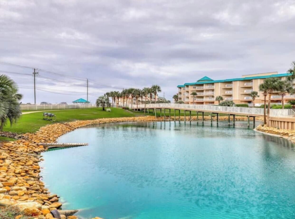 A resort with a large pool, a bridge, and a building with balconies.