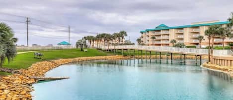 A resort with a large pool, a bridge, and a building with balconies.