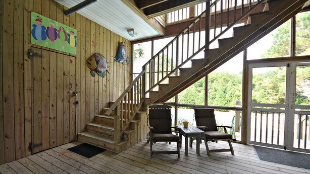 A wooden deck with a staircase, two chairs, and a table. - Private Pool - Litchfield Beach - Second Row (Pawleys Island)