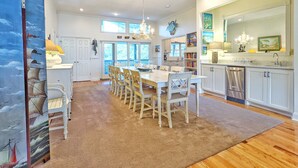 A spacious kitchen with a dining area, wooden flooring, and a large window providing natural light. - Private Pool - Litchfield Beach - Second Row (Pawleys Island)