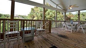 A covered outdoor deck with wooden flooring, white chairs, a glass table, and a ceiling fan. - Private Pool - Litchfield Beach - Second Row (Pawleys Island)