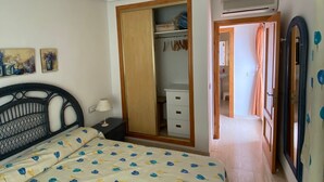 Una camera da letto con un letto, un armadio, uno specchio e un corridoio che dà su un'altra stanza.