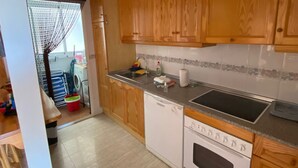 Una cucina con mobili in legno, una lavastoviglie, un fornello e un lavandino.
