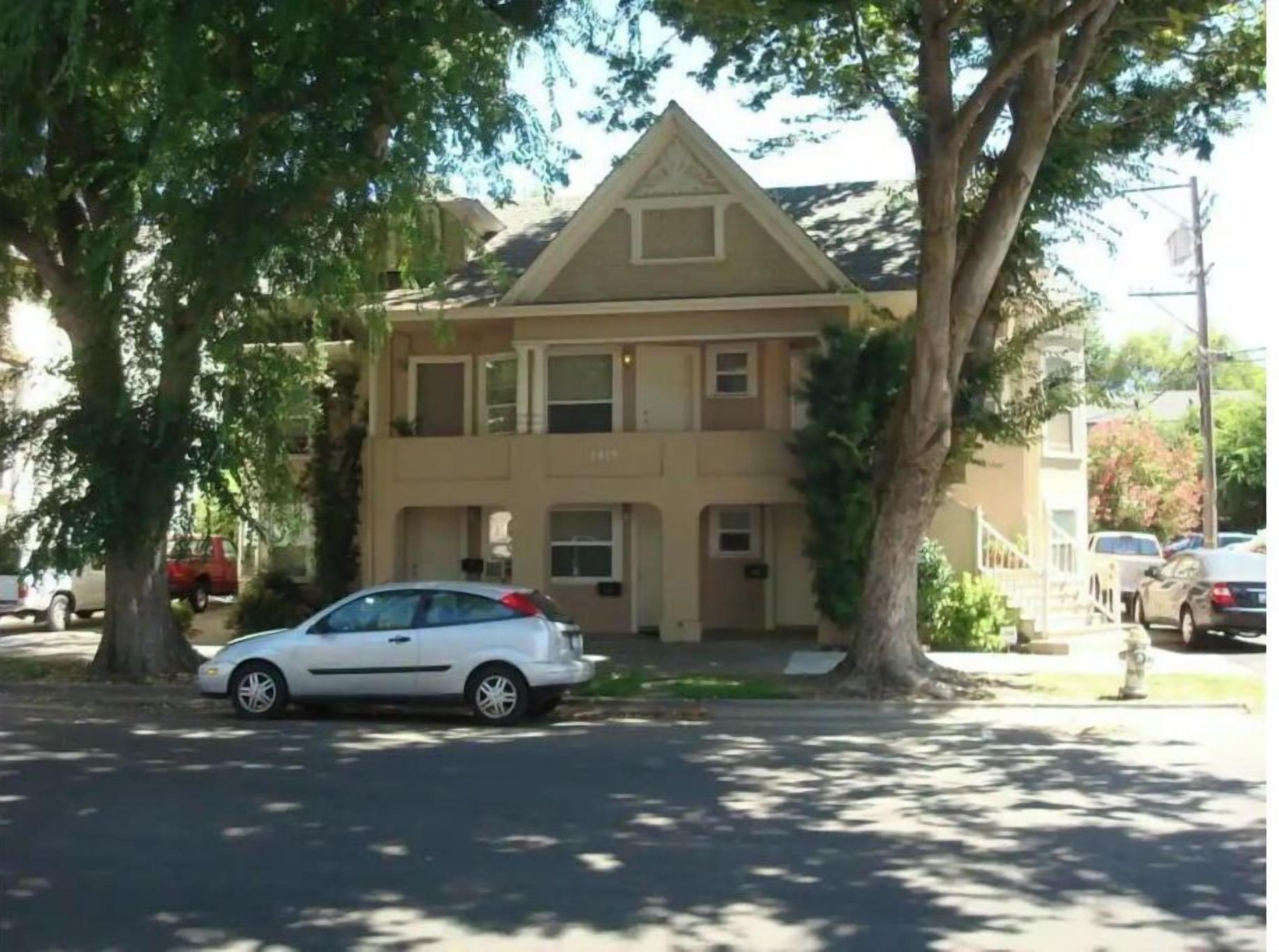 A two-story house with a front porch and a car parked in front.