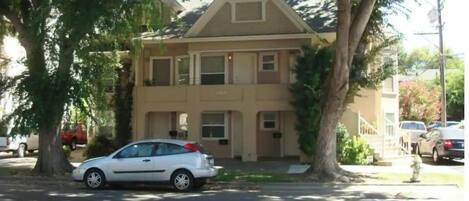 A two-story house with a front porch and a car parked in front.