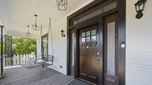 Une véranda avec un plancher en bois, une porte marron foncé et deux lanternes suspendues.