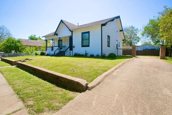A two-story house with a front porch, a driveway, and a well-maintained lawn.