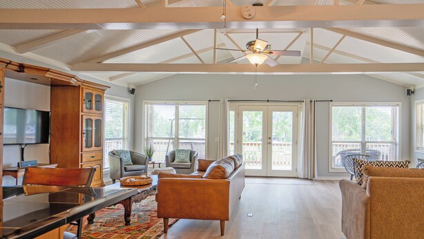 A spacious living room with a high ceiling, large windows, and a ceiling fan. - Creek Front Home w/ Fishing Pier & Amazing Outdoor Spaces (Sargent)