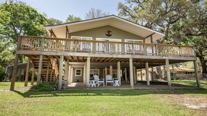 A two-story building with a balcony and outdoor seating area. - Creek Front Home w/ Fishing Pier & Amazing Outdoor Spaces (Sargent)