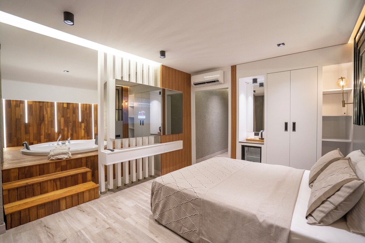 Une chambre moderne avec un grand lit, une coiffeuse intégrée avec un miroir, un escalier en bois et un dressing.