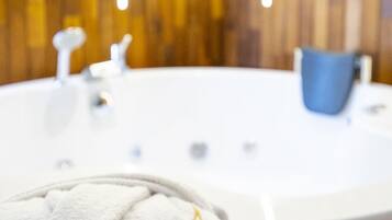 A bathroom with a white bathtub, a blue bucket, and a towel with text.