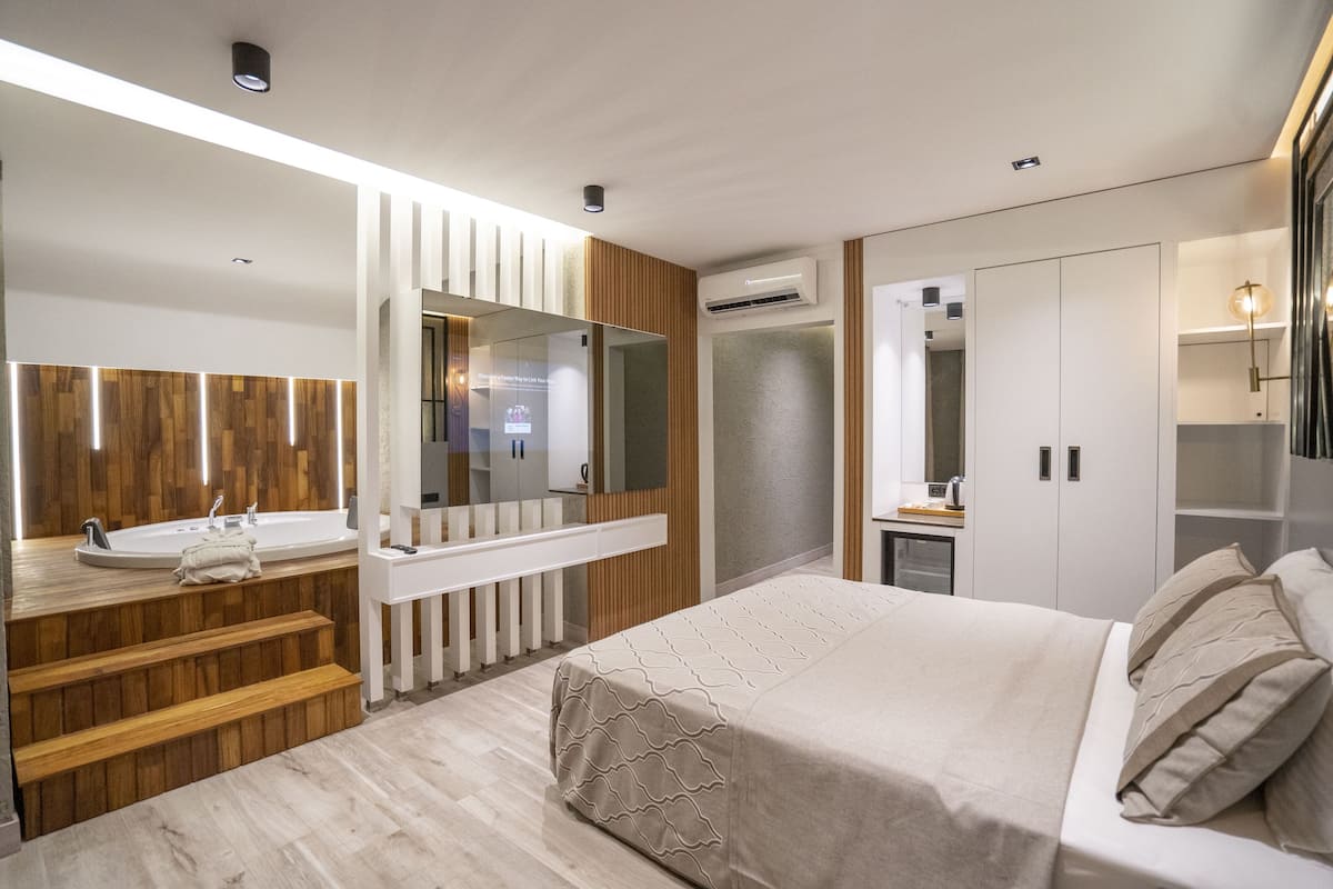 Een moderne slaapkamer met een groot bed, een kaptafel met spiegel en een trap naar een hoger gelegen verdieping.