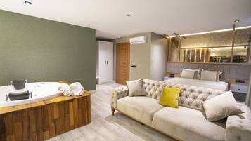 A modern bedroom with a large bed, a wooden vanity, and a built-in bathtub.