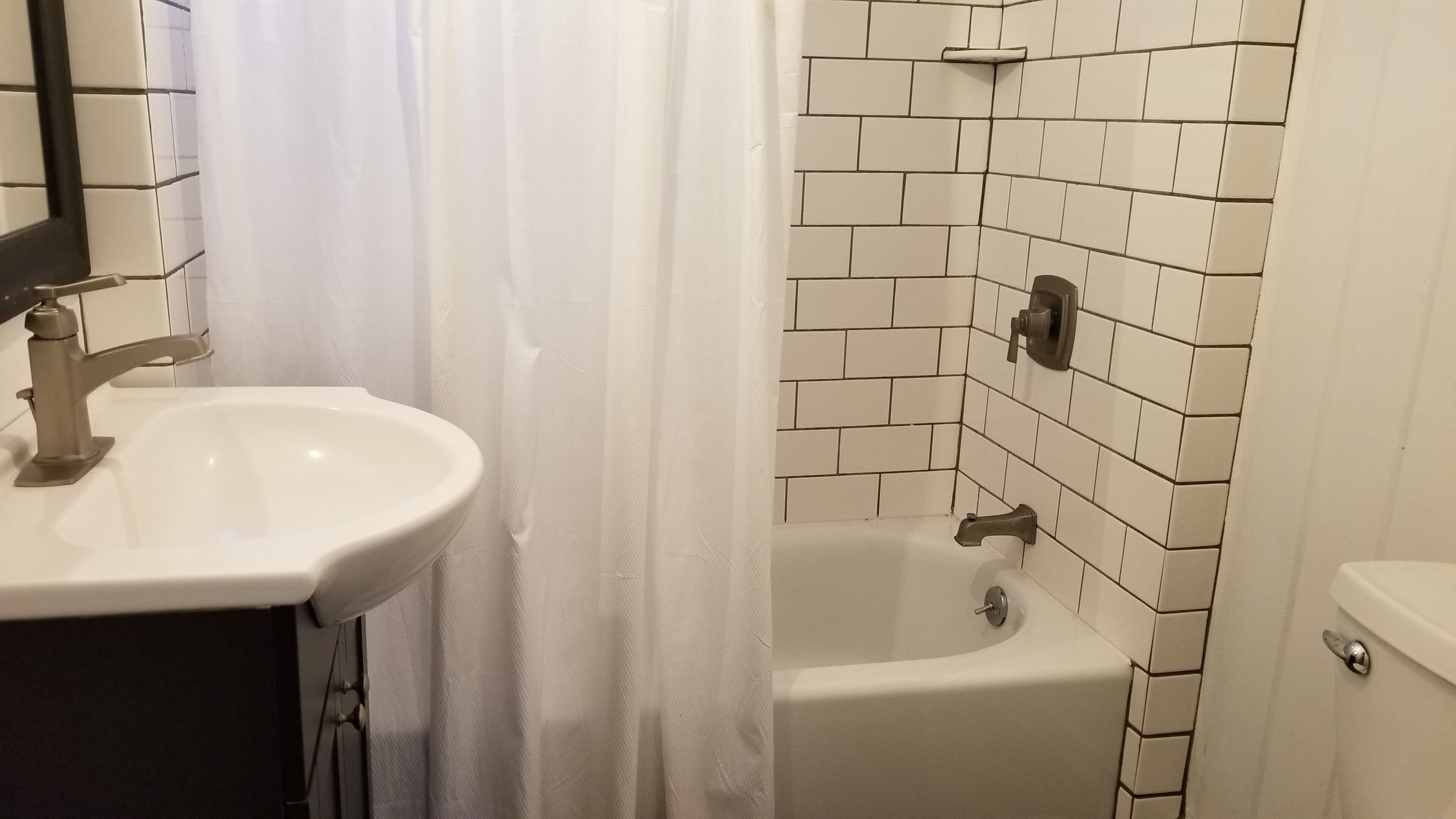 A bathroom with a white sink, a bathtub, and a toilet.