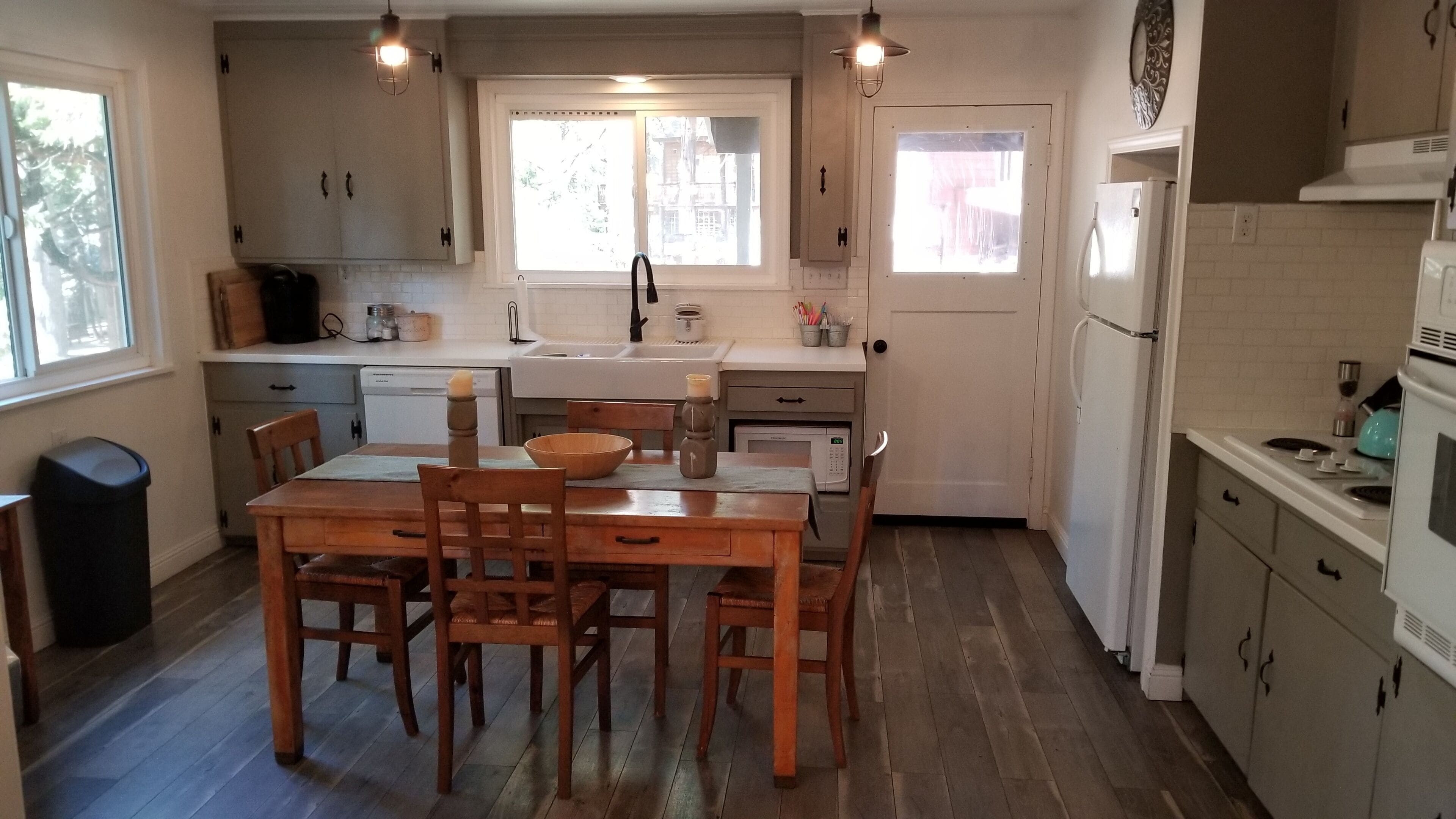 A kitchen with wooden cabinets, a dining table with chairs, a sink, a refrigerator, and a window with a view of buildings.