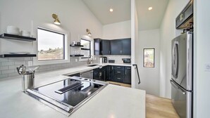 Une cuisine moderne dotée d’un îlot central, d’appareils électroménagers en acier inoxydable et de meubles de couleur noire.
