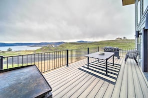 A wooden deck with a table and chairs, overlooking a body of water and hills. - Modern Davenport Home w/ Water View & Grill! (Davenport)