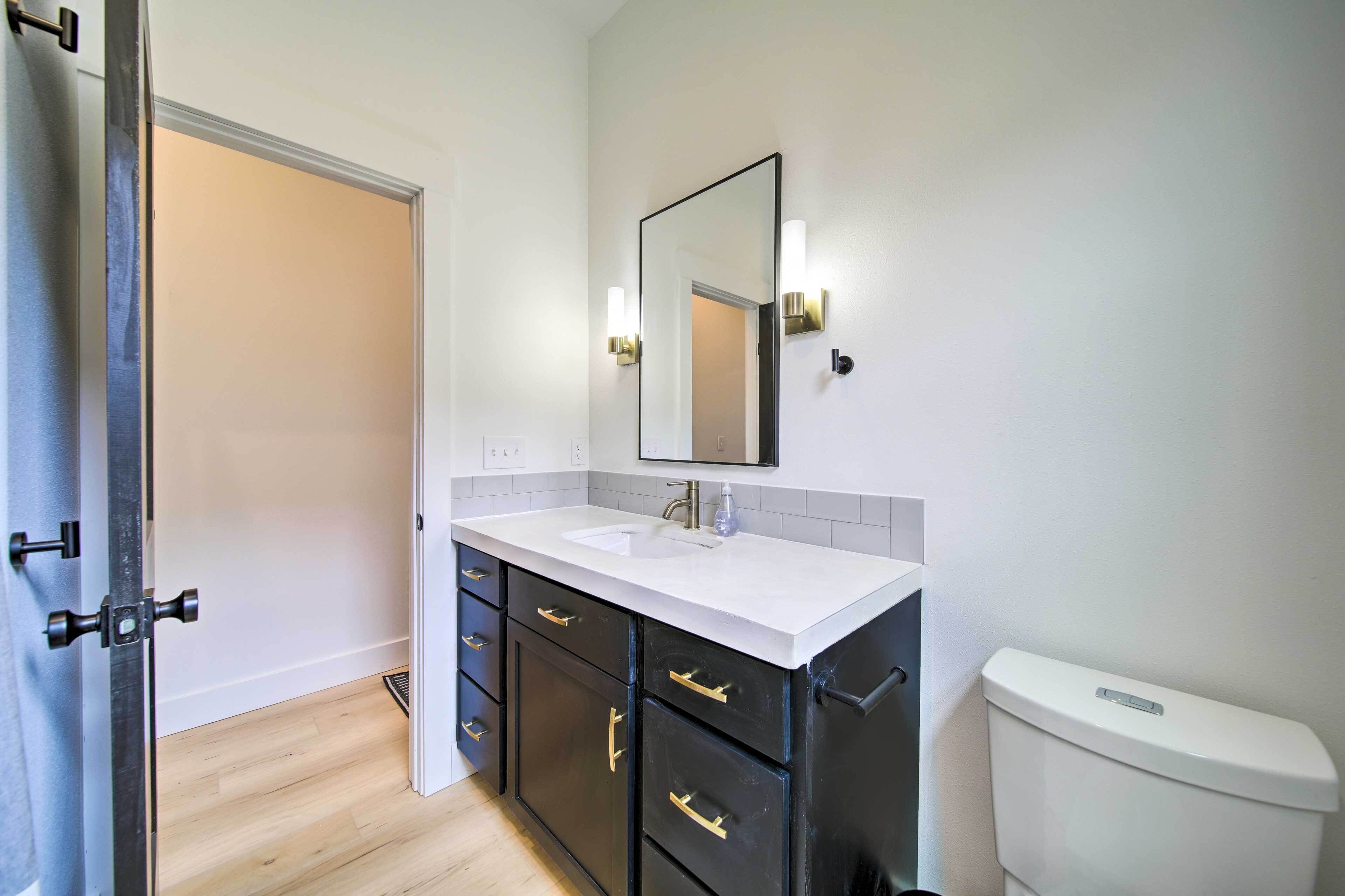 Une salle de bain avec un lavabo blanc, des meubles noirs, un miroir et des toilettes.