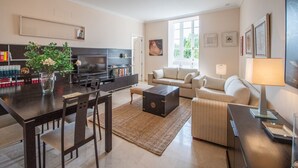 A modern living room with a dining area, a sofa, a coffee table, and a TV. - Cadiz Meridian Apartment (Cádiz)