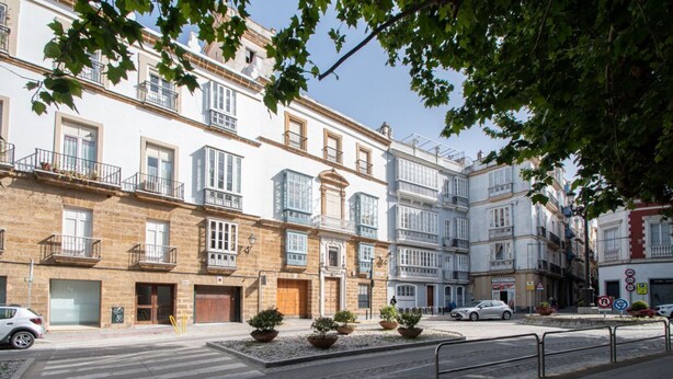 A row of multi-story buildings with balconies, a pedestrian crossing, and a street with cars. - Cadiz Meridian Apartment (Cádiz)