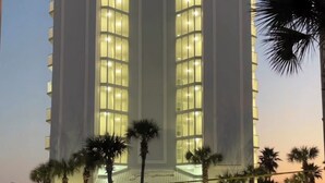 A multi-story hotel with a central atrium and large windows.