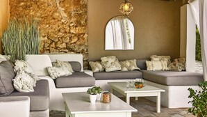A cozy outdoor seating area with a stone wall, a hanging light fixture, and a large mirror. - Manor House at Masia Nur Sitges ( adults only, very stylisch)  ) (Canyelles)