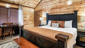 Ein Schlafzimmer mit Holzwänden, einem Bett, Nachttischen, einem Sessel und einem Schreibtisch.