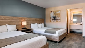A hotel room with two beds, a nightstand with a lamp, a painting on the wall, and a bathroom visible through an open door. - Hotel Dunas (Ciudad Juárez)