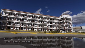 A multi-story hotel with a reflective parking lot and a clear blue sky. - Hotel Dunas (Ciudad Juárez)