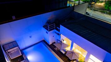 Un área de piscina en la azotea con sombrillas y sillones de descanso.