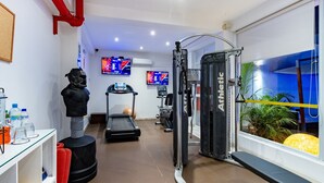 Une salle de sport équipée de tapis de course, d’appareils de musculation et d’un sac de frappe.