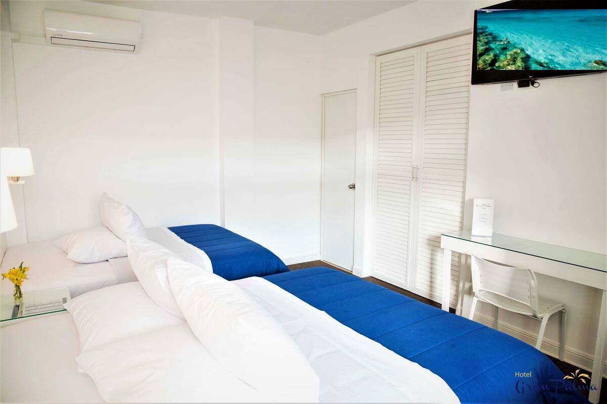 Quarto de hotel com cama, escrivaninha e televisão.