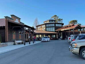 Un bâtiment doté d’une tour centrale et d’une zone couverte devant laquelle est garée une voiture.