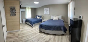 Habitación de hotel con dos camas, un televisor y un cartel con normas.
