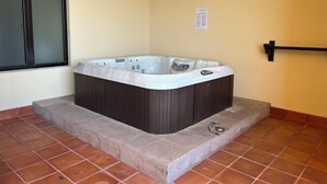 A hot tub in a corner with a window and a sign on the wall. - Room with a view of the Pacific and a private Jacuzzi at Sunset Beach Resort (Cabo San Lucas)