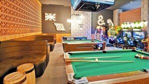 A pool table with green felt, wooden stools, and a seating area with wooden benches. - Room with a view of the Pacific and a private Jacuzzi at Sunset Beach Resort (Cabo San Lucas)
