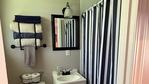 A compact bathroom with a toilet, sink, and a shower curtain. - Motel at KY Lake. Stars & Stripes. (Gilbertsville)