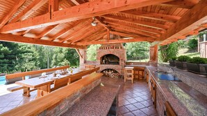 Un patio al aire libre con horno de ladrillo, bancos de madera, una mesa y un lavamanos.