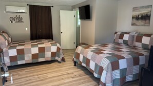 A bedroom with two beds, a flat-screen TV, and a painting on the wall. - Motel at KY Lake. Reel & Relax (Gilbertsville)